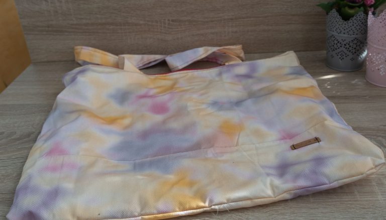 Beige Tasche mit farbigen, wolkenartigen Mustern in Lila, Rosa und Gelb.